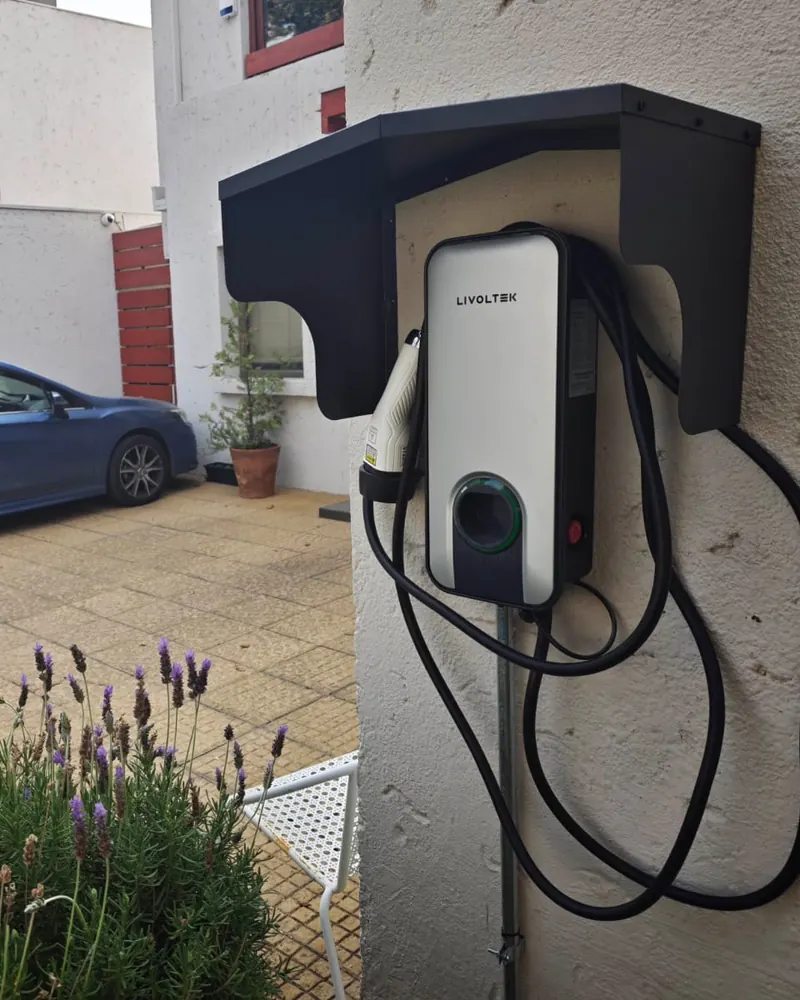Cargador Livoltek bajo un techo protector metálico en el patio de una casa